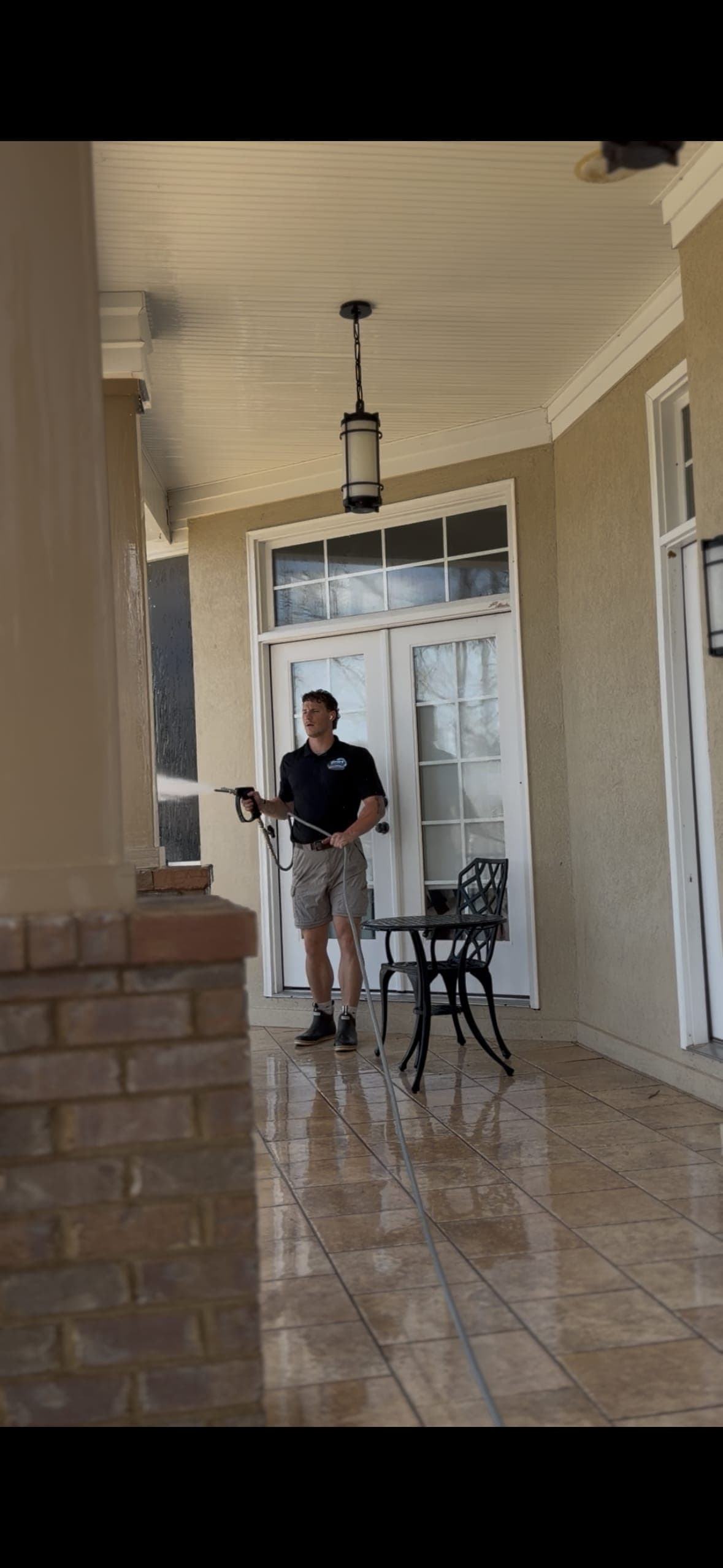 Technician pressure washing covered porch